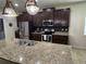 A well-lit kitchen featuring dark cabinets, granite countertops, stainless appliances, and a large island with a sink at 5821 Hevena Ct, Palmetto, FL 34221