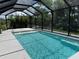 A screened in in-ground pool is surrounded by tropical foliage and a black metal fence at 5821 Hevena Ct, Palmetto, FL 34221
