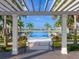 Framed view of the community pool and lake, flanked by palm trees and covered seating areas at 712 Crosswind Ave, Sarasota, FL 34240