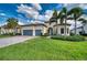 Charming home features a well-manicured lawn, palm trees, and a paver driveway at 7760 Grande Shores Dr, Sarasota, FL 34240