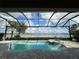 Screened pool with brick trim and spa overlooking a lake with blue skies and white clouds at 7760 Grande Shores Dr, Sarasota, FL 34240