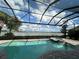 Screened-in pool and spa overlook a tranquil lake with blue skies and a few white clouds at 7760 Grande Shores Dr, Sarasota, FL 34240