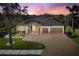 Beautiful home featuring a spacious driveway, well-manicured lawn, and a tile roof at dusk at 12810 Daisy Pl, Bradenton, FL 34212