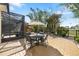 Outdoor patio featuring a dining table with chairs surrounded by tropical landscaping and a partial view of a screened enclosure at 12810 Daisy Pl, Bradenton, FL 34212