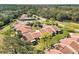 Aerial view of townhomes with well-manicured lawns, red tile roofs, and mature trees at 3629 Longmeadow # 38, Sarasota, FL 34235