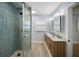 Stylish bathroom featuring double sinks, wood cabinets, glass shower with a tiled floor, and modern lighting at 400 Dona Dr, Nokomis, FL 34275
