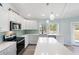Bright kitchen features white cabinets, stainless steel appliances, island seating, and quartz countertops at 400 Dona Dr, Nokomis, FL 34275
