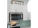 Modern kitchen with white cabinets, stainless steel microwave, stove, and light green subway tile backsplash at 400 Dona Dr, Nokomis, FL 34275