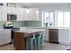 Bright kitchen features white cabinets, stainless steel appliances, island seating, and tile backsplash at 400 Dona Dr, Nokomis, FL 34275