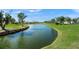 Picturesque view of a pond surrounded by manicured green grass, with charming residential homes in the background at 4410 Murfield E Dr, Bradenton, FL 34203