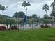 Community pool surrounded by lush landscaping, palm trees, and a black metal fence at 7211 W Country Club N Dr # 135, Sarasota, FL 34243