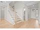 Bright hallway with wood staircase leading up and a view into a powder room at 8609 Evening Dr, Sarasota, FL 34241