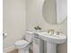 Elegant half bath with pedestal sink, round mirror, and modern gold hardware at 8609 Evening Dr, Sarasota, FL 34241