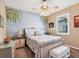 Comfortable bedroom features a decorative mural, a ceiling fan, and ample natural light from the window at 13811 Nighthawk Ter, Lakewood Ranch, FL 34202