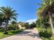 View of the brick driveway leading to a well-maintained home with palm trees and a lush yard at 15207 17Th E Ave, Bradenton, FL 34212