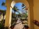 View through an archway showing a brick path leading to a home surrounded by lush landscaping and palm trees at 15207 17Th E Ave, Bradenton, FL 34212