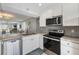 Modern kitchen with stainless appliances, sleek cabinetry, and a view into the living room at 276 Cerromar Way # 60, Venice, FL 34293