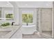 Bright bathroom showcasing a soaking tub next to a window offering exterior views and a glass enclosed shower stall at 3651 Walden Pond Dr, Sarasota, FL 34240