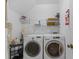 Efficient laundry room featuring white washer and dryer with shelving for storage at 5684 Duval St, Bradenton, FL 34203