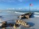 Scenic beach with an old pier ruin extending into turquoise waters, complemented by a clear sky and sandy shore at 5780 Midnight Pass Rd # 303B, Sarasota, FL 34242