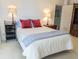 Comfortable bedroom with carpet, king size bed, decorative lamps, and two small side tables at 5780 Midnight Pass Rd # 303B, Sarasota, FL 34242