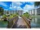 Picturesque view of the condos across the water with a charming wooden bridge surrounded by lush landscaping and palm trees at 5780 Midnight Pass Rd # 303B, Sarasota, FL 34242