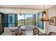 Inviting sun room boasts tile flooring, dining table, chandelier, and stunning views of landscaping, water, and community buildings at 5780 Midnight Pass Rd # 303B, Sarasota, FL 34242
