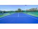 Well-maintained blue tennis court surrounded by green fencing and trees at 5780 Midnight Pass Rd # 303B, Sarasota, FL 34242
