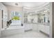 Bright and airy bathroom with a soaking tub under an arched window and dual sinks with vanity at 6626 The Masters Ave, Lakewood Ranch, FL 34202