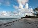 Scenic beach view with gentle waves lapping the shore under a partly cloudy sky at 741 Hideaway Bay Dr, Longboat Key, FL 34228