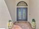 Elegant double front doors with decorative ironwork, potted plants, and a brick paver walkway at 16531 Kendleshire Ter, Bradenton, FL 34202