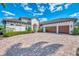 Elegant home featuring a brick driveway, barrel tile roof, manicured landscaping, and a three-car garage at 16531 Kendleshire Ter, Lakewood Ranch, FL 34202