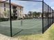 Well maintained tennis court enclosed by chain-link fencing with trees in the background at 25188 Marion Ave # E208, Punta Gorda, FL 33950