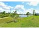 Lush backyard with a scenic pond, mature trees, and a clear blue sky offers serene privacy at 309 Potenza Loop, Nokomis, FL 34275