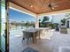 Covered outdoor patio with a dining table, grill, and lounge chairs overlooking the canal and tropical landscape at 355 W Royal Flamingo Dr, Sarasota, FL 34236