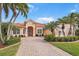 Charming home features a red tile roof, brick driveway, lush landscaping, and stately palm trees at 4245 Corso Venetia Blvd, Venice, FL 34293