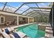 Screened in pool and spa surrounded by patio furniture, an outdoor kitchen and green landscaping at 4931 Hidden Oaks Trl, Sarasota, FL 34232