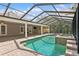 Screened in pool and spa surrounded by patio furniture, an outdoor kitchen and green landscaping at 4931 Hidden Oaks Trl, Sarasota, FL 34232