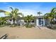 Beautiful single-story home boasting a bright blue front door and lush tropical landscaping with mature palms at 504 Bayview Dr, Holmes Beach, FL 34217