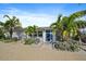 Charming single-story home featuring a bright blue front door and lush tropical landscaping with mature palms at 504 Bayview Dr, Holmes Beach, FL 34217