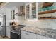 Modern kitchen with stainless steel appliances, stylish backsplash, granite countertops, and glass front cabinets at 504 Bayview Dr, Holmes Beach, FL 34217