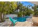 Inviting outdoor pool area with colorful furniture and privacy fence surrounded by tropical trees at 5807 De Palmas Ave, Holmes Beach, FL 34217