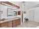 Bright bathroom features granite countertops, dark wood cabinets, a framed mirror and a travertine tile floor at 6612 Saint James Xing, University Park, FL 34201