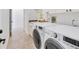 Convenient laundry room with a full-size washer and dryer and travertine flooring at 6612 Saint James Xing, University Park, FL 34201
