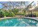 The backyard features a clear-view screened enclosure and pool surrounded by lush landscaping at 6612 Saint James Xing, University Park, FL 34201