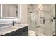 Modern bathroom featuring a luxurious glass shower with white marble tile and a dark vanity with a lighted mirror at 1210 Gulf Blvd, Englewood, FL 34223