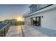 Rooftop deck with modern railings and gray and white stone tile flooring, leading to sliding glass doors of the building at 1210 Gulf Blvd, Englewood, FL 34223