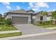 Charming gray home featuring a spacious garage, manicured landscaping, and a brick driveway at 2081 Gardenia Ave, Port Charlotte, FL 33953