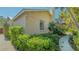 Exterior view of the house featuring tropical landscaping, neutral stucco, and a walkway at 2377 Burton Ln, Sarasota, FL 34239