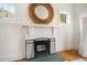 White brick fireplace featuring a decorative wicker mirror and a protective metal screen at 2524 11Th W Ave, Bradenton, FL 34205